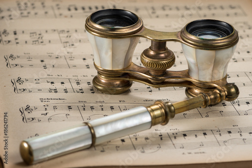 Old antique opera glasses lying on musical scores
