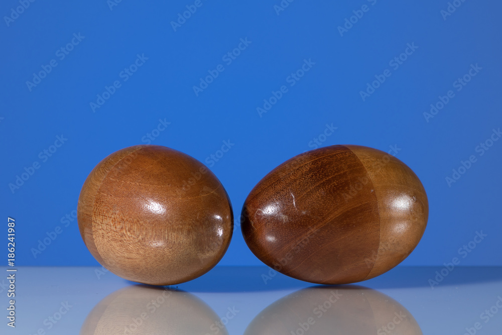 Two wooden egg shaker in front of a blue background Two wooden egg shaker in front of a blue background