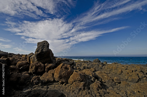 Steinige Meeresküste mit spektakulärem Wolkenhimmel.
