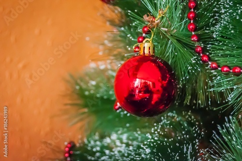 A beautiful red ball on a Christmas tree (or a New Year tree) with beautiful festive decoration ornament. New Year concept