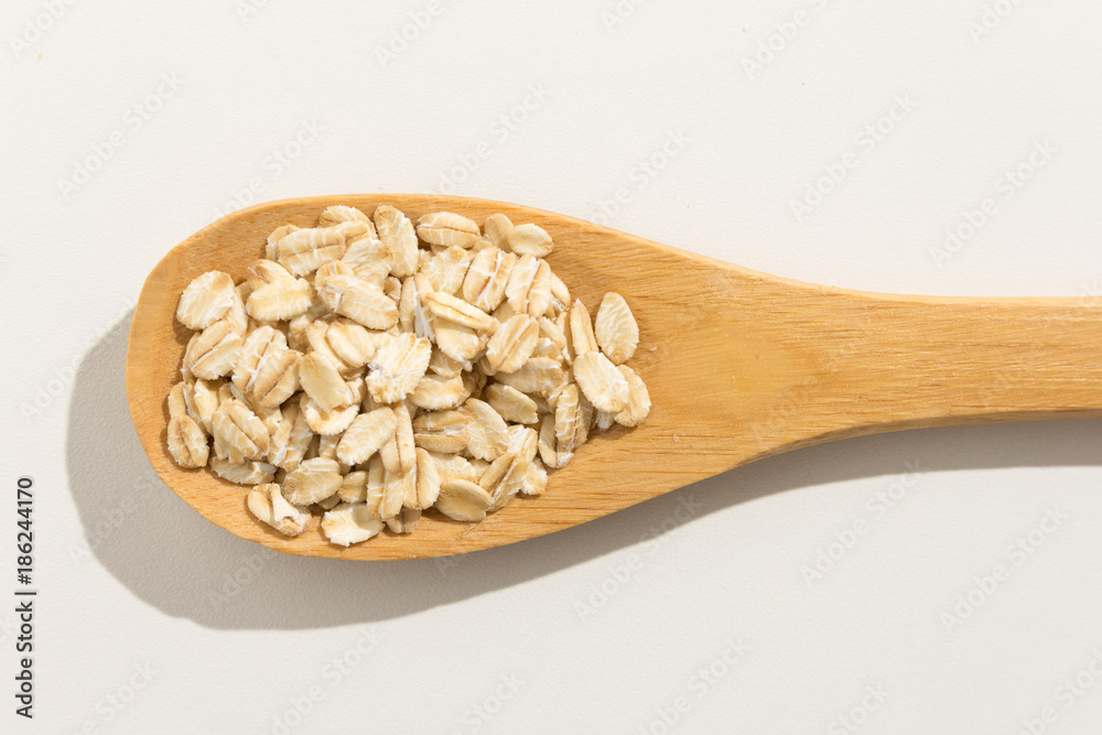 Oat cereal grain. Nutritious grains on a wooden spoon on white background.