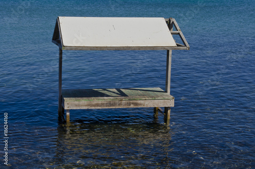 Überdachter Holztisch der im Wasser steht.
