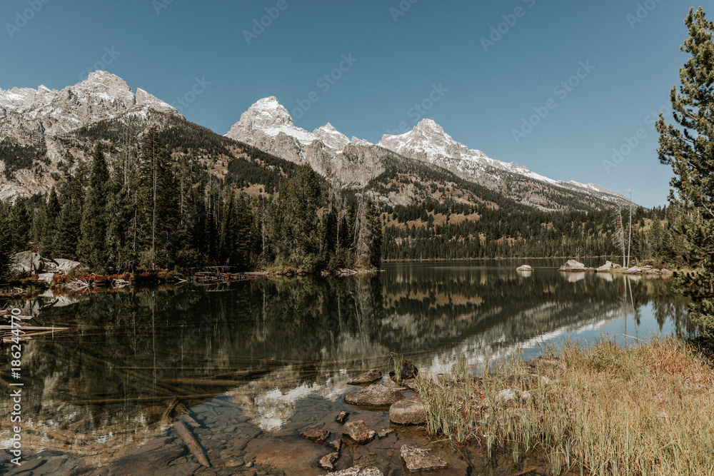 Still water of Taggart Lake reflects the mountains and clouds