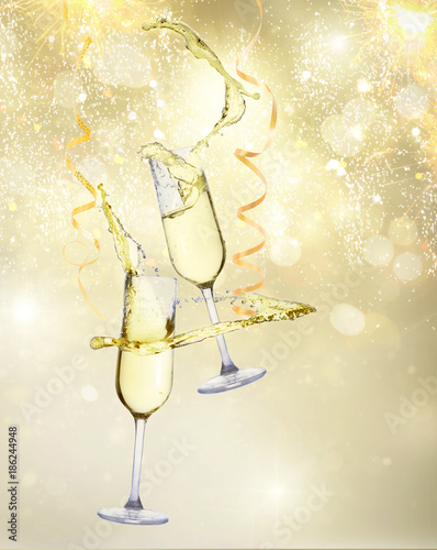 Two festive champagne glasses with streaming paper on golden bokeh background with lights