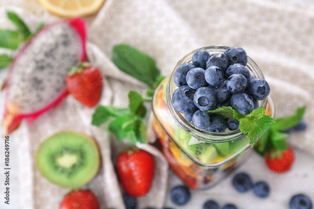 Mason jar with fruits and berries on table