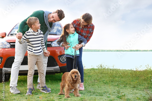 Young family with cute children and dog near car