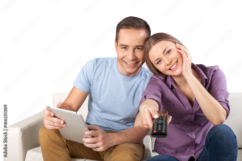 Fototapeta premium Smiling Couple Using Remote Control and Tablet