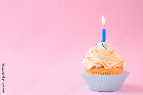 Tasty cupcake with candle on color background