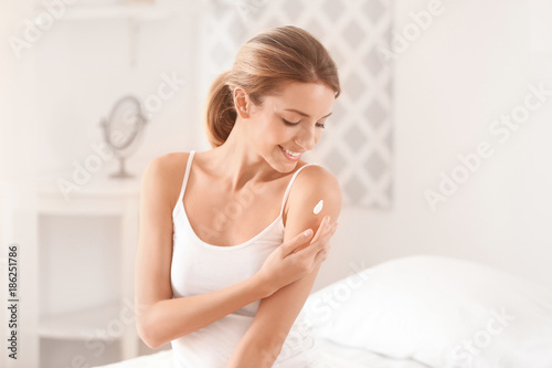 Young woman applying body c...