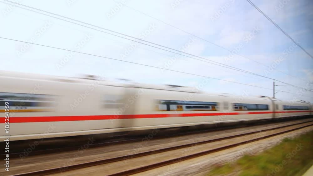 View from the window on oncoming train. View from window to passing train on railroad. Summer journey by train past natural landscape