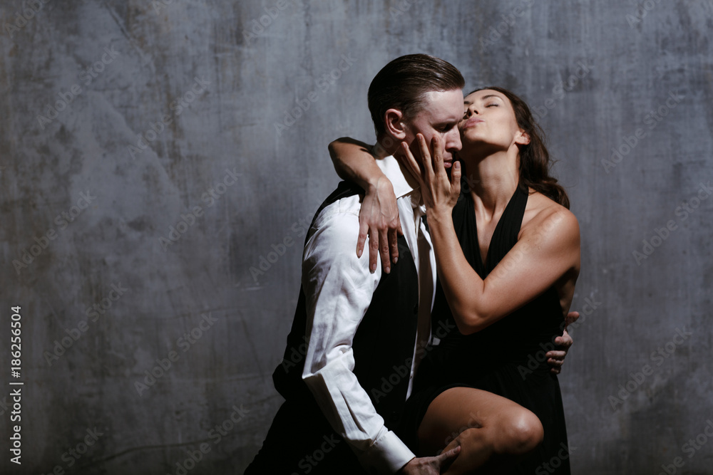 Obraz premium Young pretty woman in black dress and man dance tango