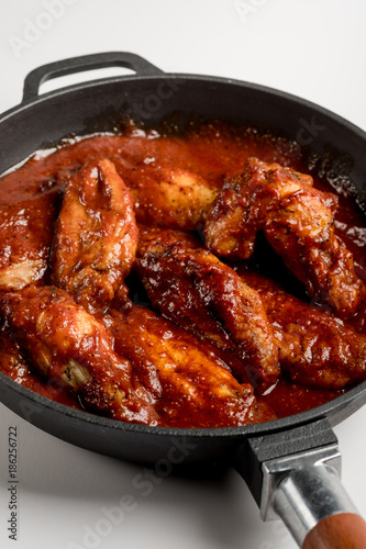 Chicken Wings BBQ in pan with red sauce. Fast food menu background isolated.