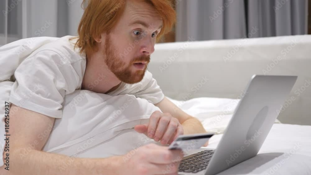 Successful Online Shopping by Redhead Beard Man in Bed, Credit Card Successful Online Shopping by Redhead Beard Man in Bed, Credit Card