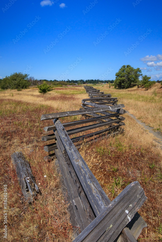 zigzag fence in the middle of grass-land under the sun with blue sky