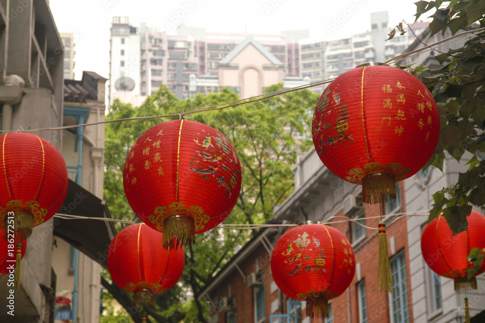 Fototapeta premium Red Lanterns Hanging Over a Hong Kong Street. Chinese New Year is celebrated with hanging red lanterns in the central district of Hong Kong. 