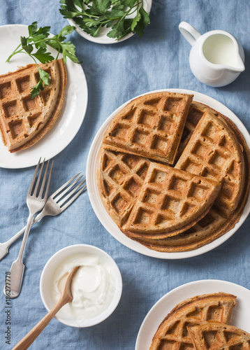 Whole wheat savory breakfast viennese waffles, cream and milk on blue background, top view