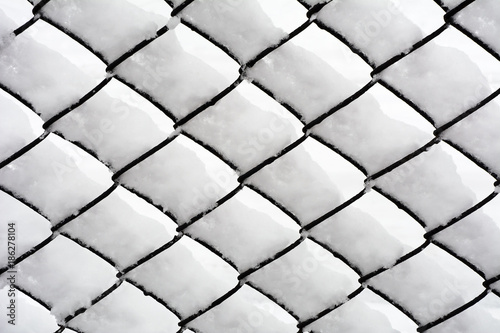 The fence mesh covered with snow. Background. Texture. 