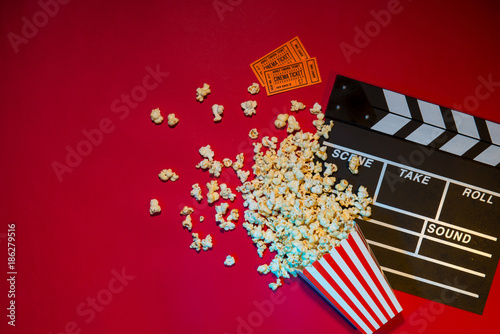 Movie tickets, clapperboard, pop corn on red background