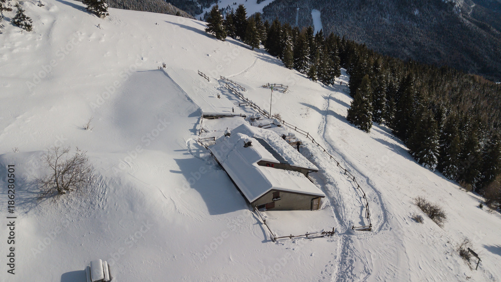 Obraz premium Drone aerial view of the lodge Cassinelli after a snow fall. Italian Alps