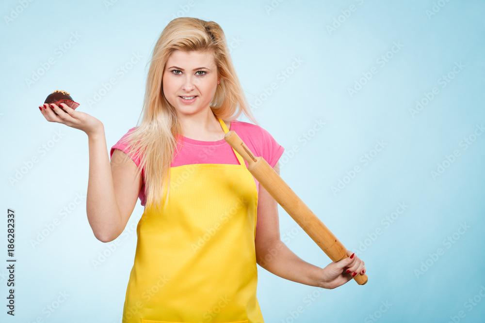 Woman holding cupcake and rolling pin wearing apron Woman holding cupcake and rolling pin wearing apron