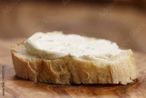 crunchy baguette slice with cream cheese on olive board