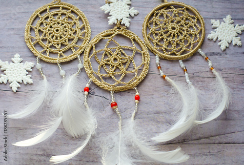 Dreamcatcher with feathers on a wooden background. Ethnic design, boho style, tribal symbol.White Christmas and New Year snowflake on a wooden vintage old background