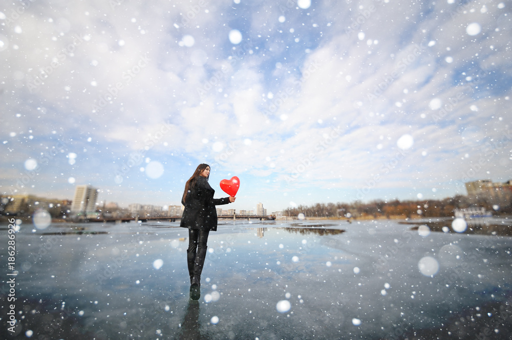 beautiful young girl with a balloon in the shape of a heart on the background of a frozen river or pond beautiful young girl with a balloon in the shape of a heart on the background of a frozen river or pond