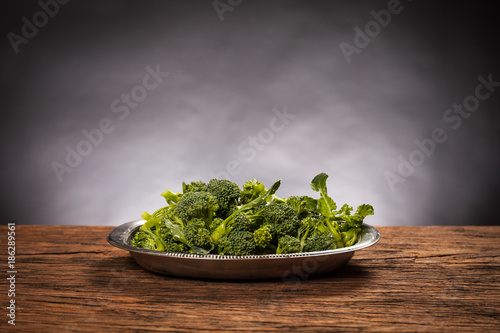 High angle view of raw broccoli bowl on a wooden table. Black background. Mediterranean food