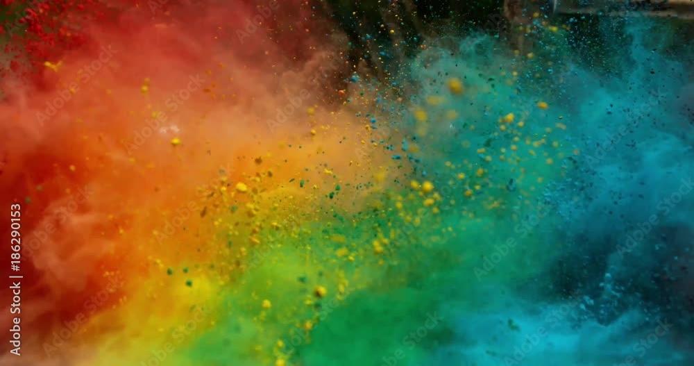 Colorful rainbow holi powder bounces off white canvas background in shockwave pattern of green blue pink and orange, slow motion, closeup