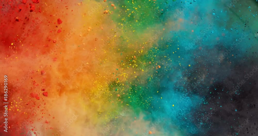 Colorful rainbow holi powder bounces off white canvas background in shockwave pattern of green blue pink and orange, slow motion, closeup