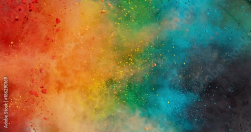Colorful rainbow holi powder bounces off white canvas background in shockwave pattern of green blue pink and orange, slow motion, closeup