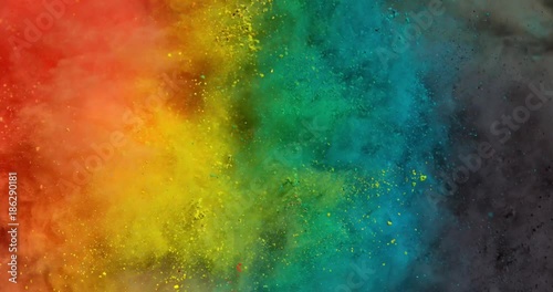 Colorful rainbow holi powder bounces off white canvas background in shockwave pattern of green blue pink and orange, slow motion, closeup