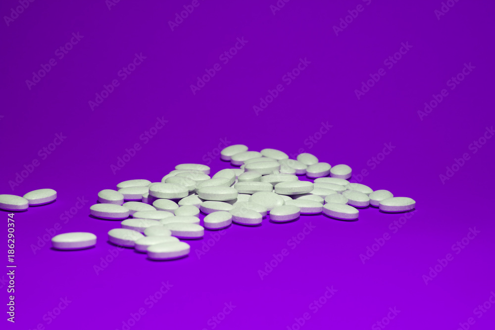Tablets with calcium on a violet background. White pills on a colored background. Tablets with calcium on a violet background. White pills on a colored background.