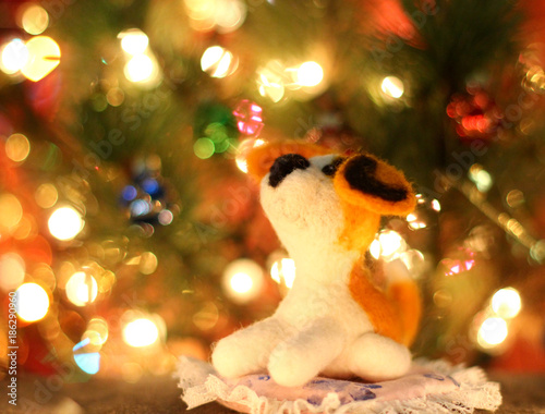 Symbol of new years 2018 yellow dog. Bolt. New years greetings background. Fancy handmade toy from wool on bokeh Christmas background. Copyspace for congratulations.