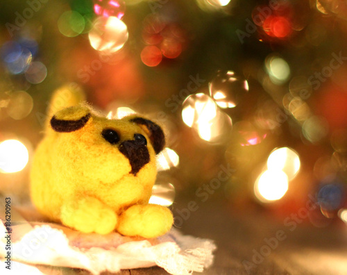 Symbol of new years 2018 yellow dog. Bolt. New years greetings background. Fancy handmade toy from wool on bokeh Christmas background. Copyspace for congratulations.