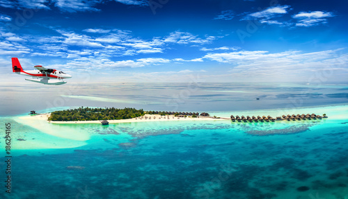Wasserflugzeug fliegt über Malediven Insel mit türkisem Wasser und feinem Sandstrand