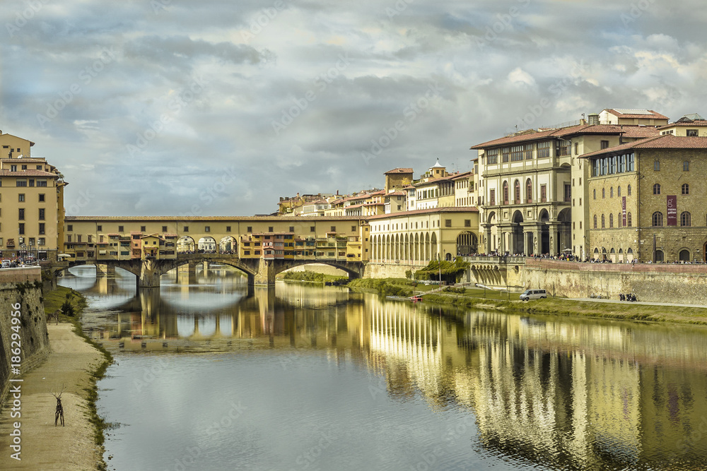 florence pontevecchio bridge in a cloudy autumn morning with historical medieval palace reflecting on the river water
