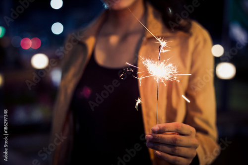 lady hold firesparkler blink in her hand at night toning photo