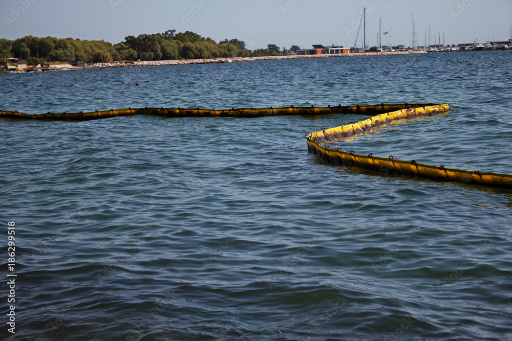 Obraz premium Floating barrier to stop pollution from oil spillage, Elliniko bay, Athens, Greece, September 14 2017. Greek oil spill spreads to Athens Riviera following the sinking of an oil tanker in Saronic Gulf.