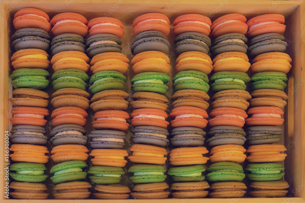 Pastel macarons display, colorful food background, repeated pattern of popular French confectionery positioned in wooden box with soft warm light filter and selective focus Pastel macarons display, colorful food background, repeated pattern of popular French confectionery positioned in wooden box with soft warm light filter and selective focus