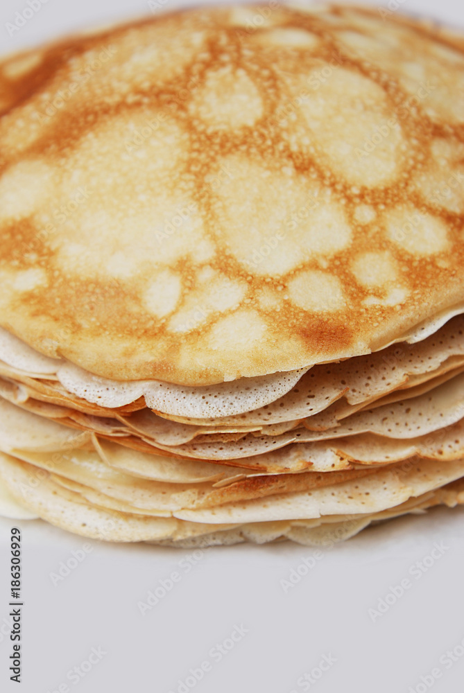 Stack of English pancakes on a round white plate on a black background. Pancake Day in Britain. Appetizing russian pancakes for Maslenitsa carnival Shrovetide . Close up. Vertical image. Stack of English pancakes on a round white plate on a black background. Pancake Day in Britain. Appetizing russian pancakes for Maslenitsa carnival Shrovetide . Close up. Vertical image.