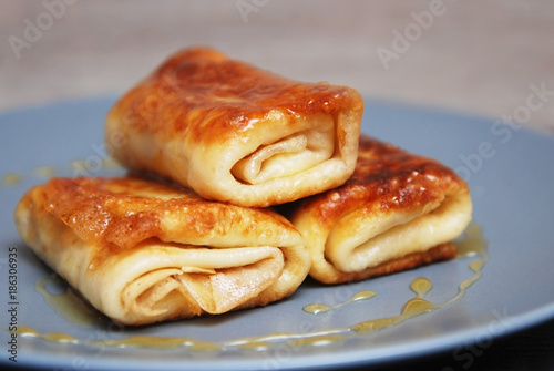 Bakery. Traditional Russian Pancakes. International Pancake Day on 28 February. Roled delicious pancakes with cheese with honey on gray plate