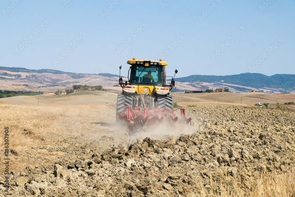 Fototapeta premium Peasant on the tractor while preparing the field for sowing