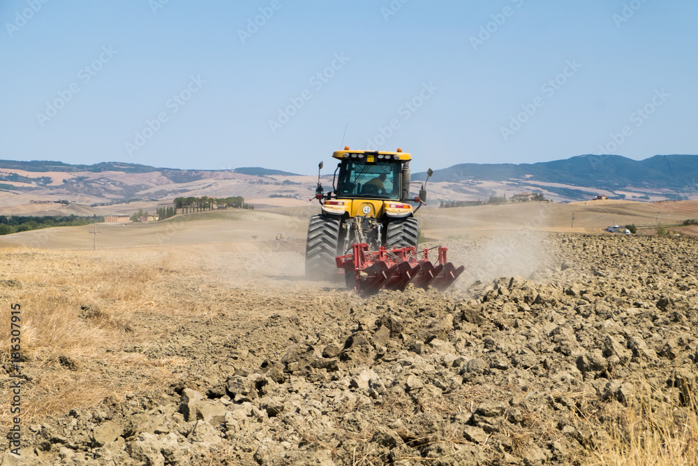 Obraz premium Peasant on the tractor while preparing the field for sowing