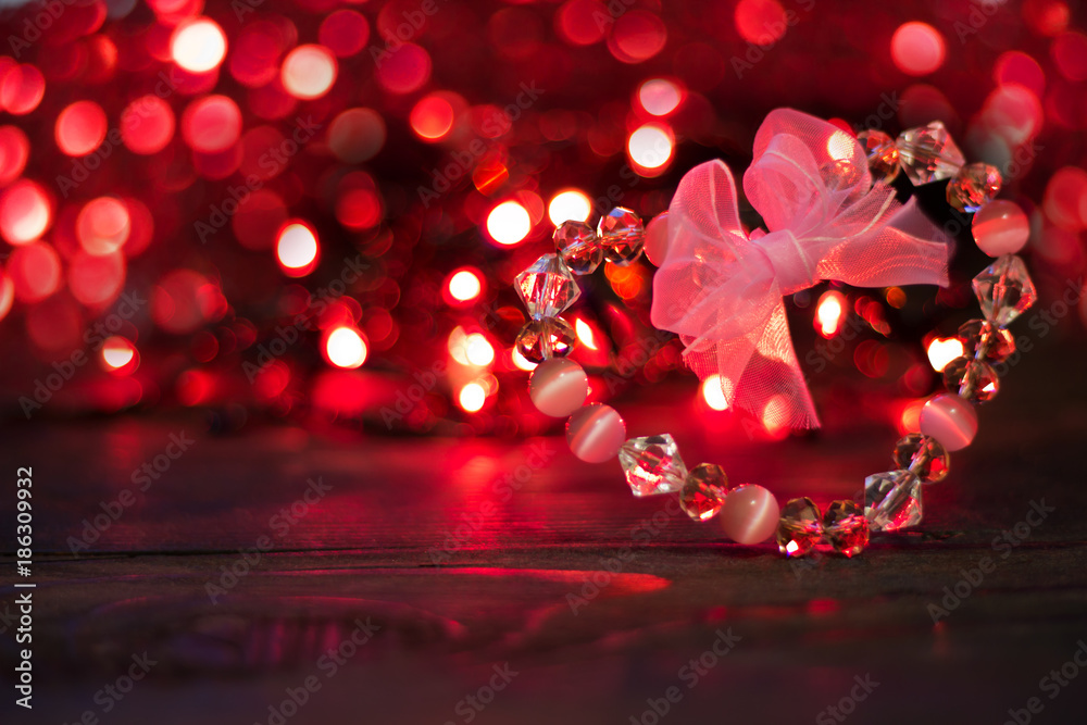 Valentine's day background.Crystal Heart with bow on background of red bokeh lights