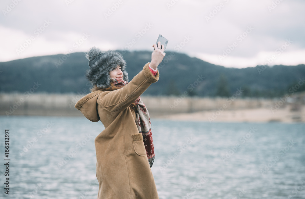 Girl taking a self portrait in front of a lake