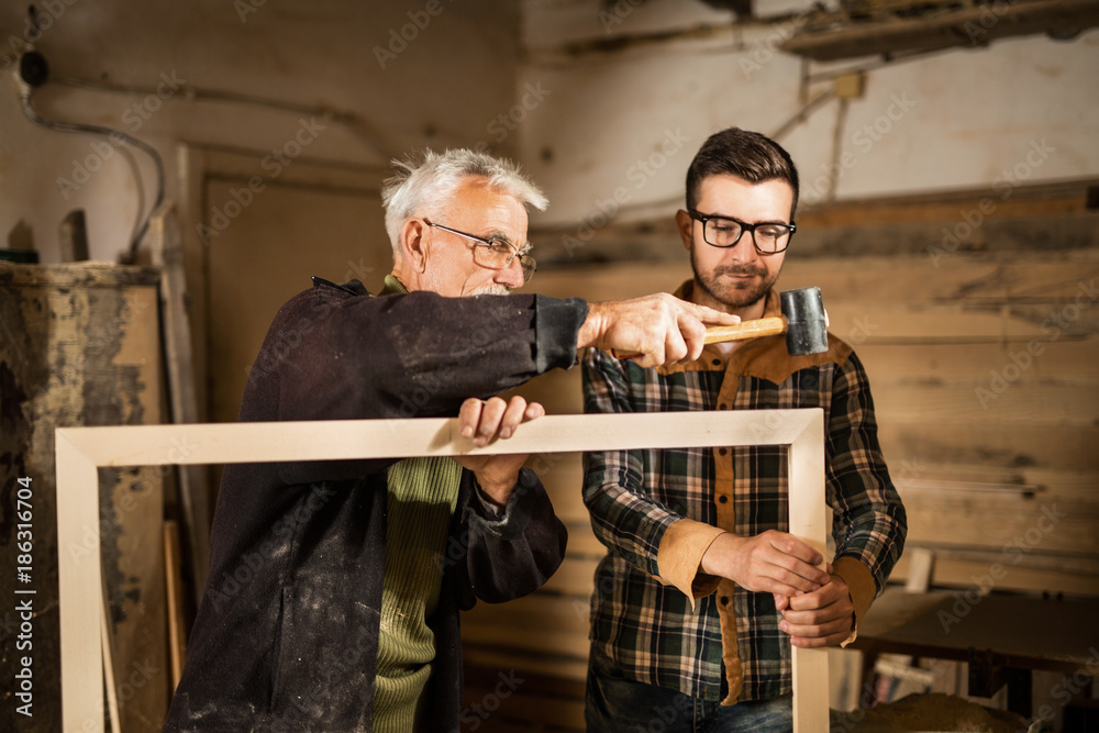 Young and senior carpenter standing in front of a camera Young and senior carpenter standing in front of a camera