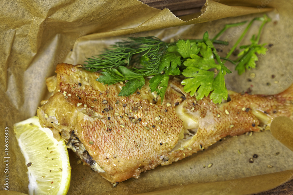 Fried fish trout, lemon and greens on paper kraft background Fried fish trout, lemon and greens on paper kraft background