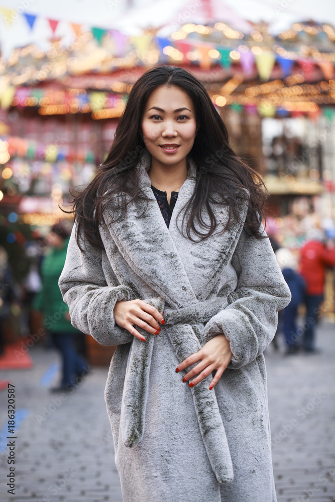 Happy asian woman in winter coat from faux fur