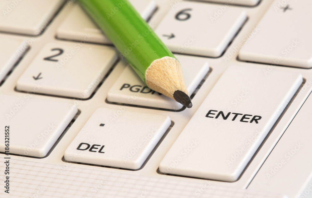 Green pencil on a white keyboard - business concept Green pencil on a white keyboard - business concept